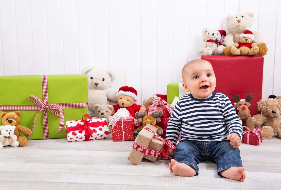 Beba u sedecem polozaju sa igrackama i poklonima.